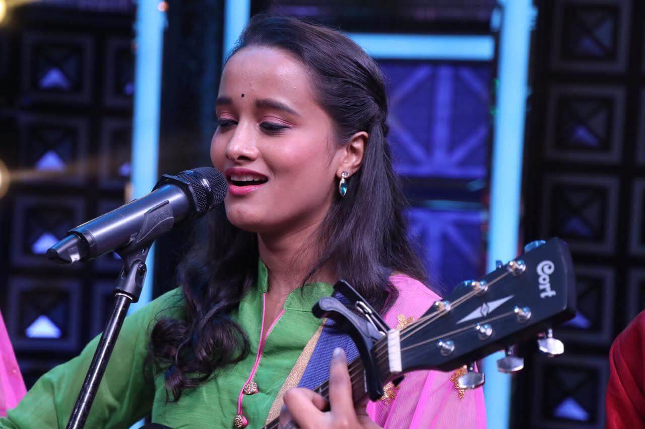 Gauri Tidke smiling on stage with guitar